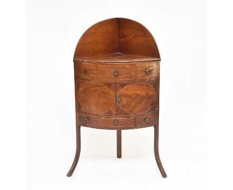 A George III mahogany, bow-fronted, corner washstand, inlaid with boxwood stringing and with an arched splashback over a late