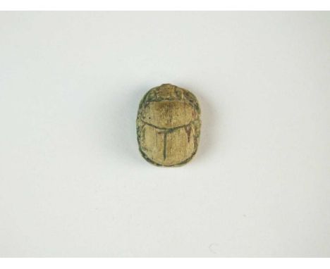 Faience scarab with details to the carapace, the legs folded to the side of the body; pierced for suspension. To the undersid