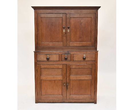 An early 19th century oak press cupboard, with bone kite-shaped escutcheons, the cavetto cornice above two panelled doors, en