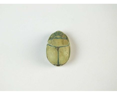 Faience scarab with detailing to the carapace, legs folded to the sides of the body; pierced for suspension. To the underside