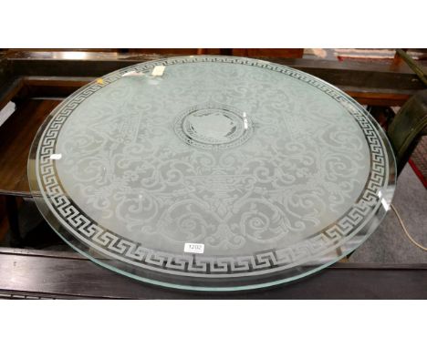 A frosted glass circular table top with etched decoration; a carved oak mantle shelf and a patinated metal console table base