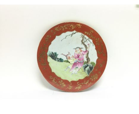 A circular ceramic plaque with hand anted decoration of figures in a garden setting, approx diameter 26.5cm. Shipping categor
