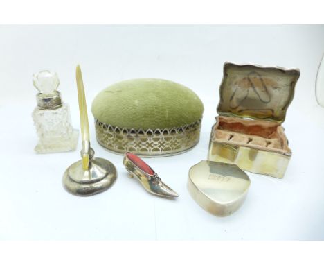 A collection of silver items; pill box, jewellery box, novelty shoe pin cushion, oval trinket box, ring stand and scent bottl