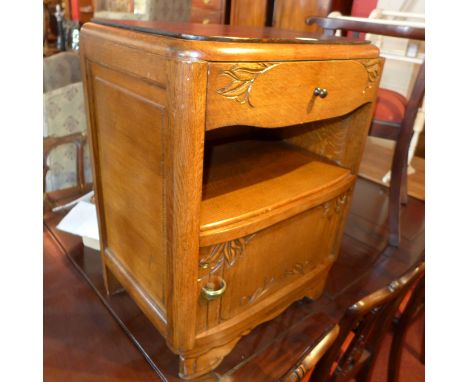 An oak bedside chest with floral carving, single drawer and raised on bracket feet. H- 66cm 