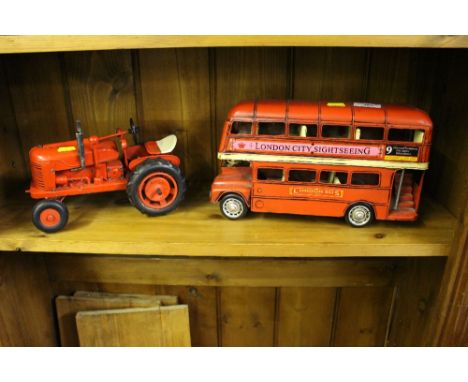 A metal London Bus together with a red painted tractor