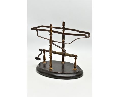A LATE 19TH / EARLY 20TH CENTURY MECHANICAL BOTTLE POURER, the worn gilt brass frame on an oval ebonised wooden base, maximum