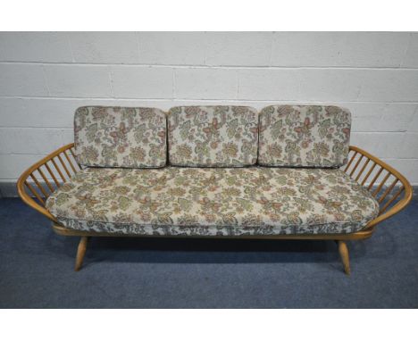 LUCIAN ERCOLANI FOR ERCOL, A MODEL 355 ELM AND BEECH STUDIO COUCH, with a surfboard back and spindled ends, with floral cushi