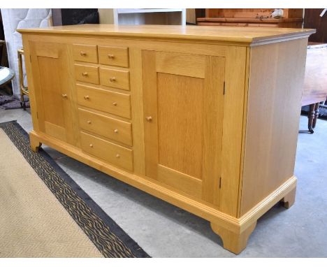 A contemporary oak sideboard centred four short over three long drawers flanked by cupboards on shaped bracket feet 185 cm x 