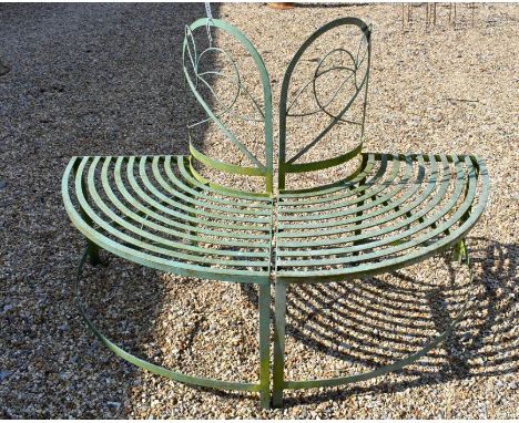 A semi-circular green painted metal garden half tree bench in two sections with strapwork seats