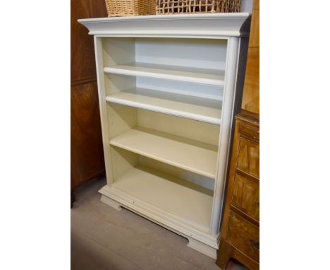 A cream-painted open bookcase with moulded top over three adjustable shelves, standing on shaped bracket feet, 101 cm wide x 