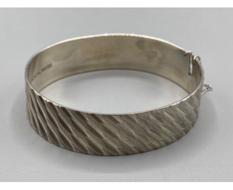 Ladies silver bangle with matt and highy polished pattern complete with safety chain