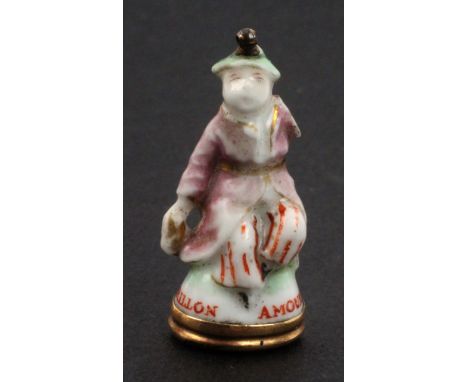 A Chelsea porcelain miniature seal, circa 1770, in the form of a China man, one arm lacking, inscribed ‘Amoureux Carillon’ in