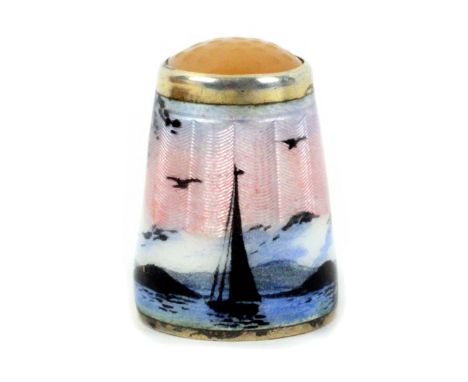 A Norwegian silver gilt and enamel thimble with pale stone top, depicting a sailing boat in a fjord with snow covered mountai