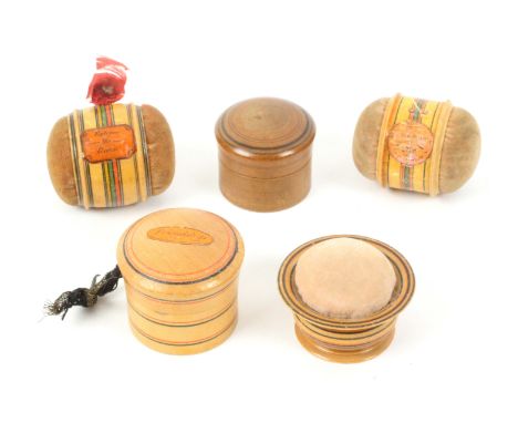 Five whitewood paint and label decorated Tunbridge ware pin cushions, comprising two double ended barrel form examples, one l