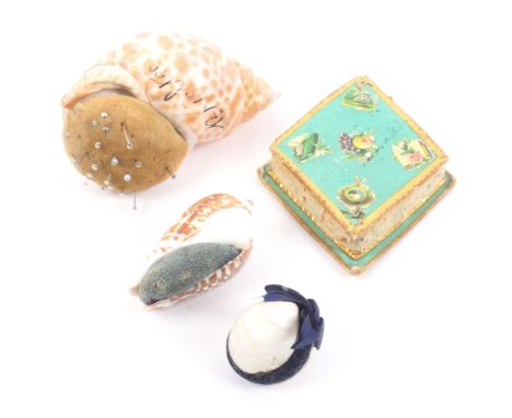 Four pin cushions, comprising three formed from sea shells, largest 7.5cms, and inscribed ‘Brighton’, and another in green ca