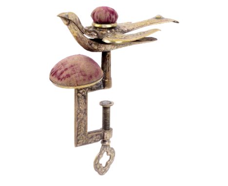 An American brass hemming bird clamp, the leaf and floral decorated rectangular frame supporting a bowl form pin cushion belo