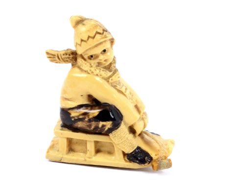A scarce celluloid novelty tape measure in the form of a child on a sledge, complete retractable tape printed in ins. and cms