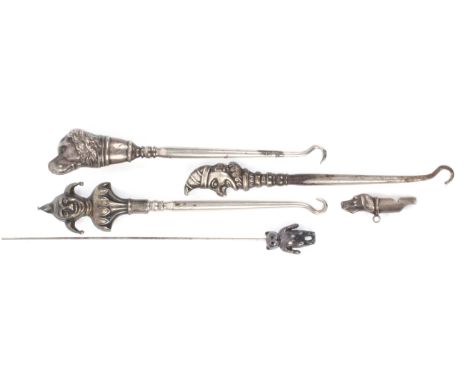 Three silver topped figural button hooks, a silver dog’s head whistle and a silver teddy bear hat pin, the button hooks compr