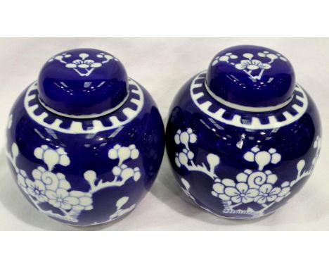 Two lidded porcelain Oriental ginger jars decorated with prunus blossoms on blue ground, no cracks or chips, H: 13 cm. P&amp;