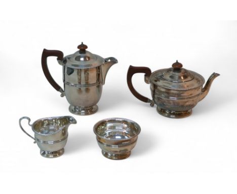 An ERII four-piece silver tea set, comprising a teapot, 23.5 by 14 by 14cm high, hot water jug, 18cm high,  (both with wooden