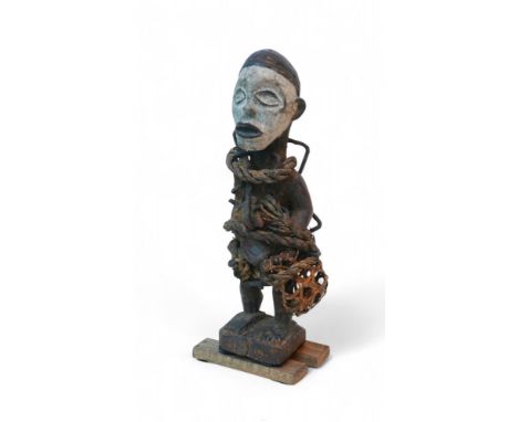 An African tribal fetish figure, with white painted face and twine and assorted metal stuck into its main body, 29cm high ove