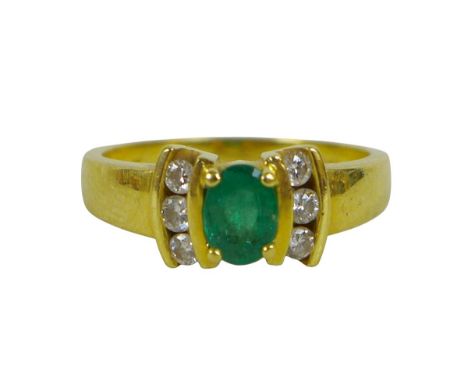 An 18ct gold, emerald and diamond ring, marked 750, oval emerald flowerhead with three diamonds each side, size N