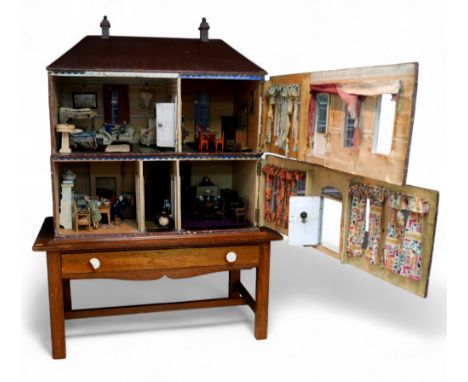 A 1930's two story dolls house on stand with contents including furniture, pictures, dolls and table ware, 81 by 43 by 111cm 