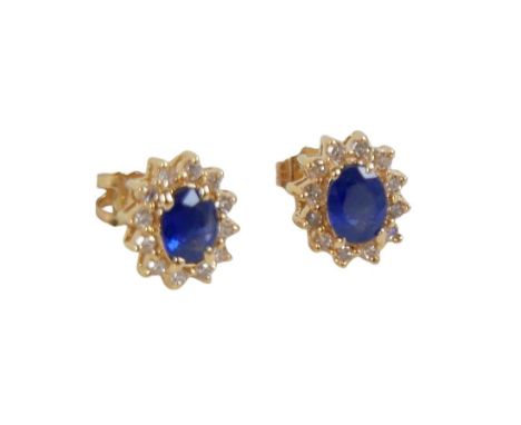 A pair of diamond and sapphire flowerhead cluster earrings, on 14k gold, the central oval sapphire surrounded by diamond chip