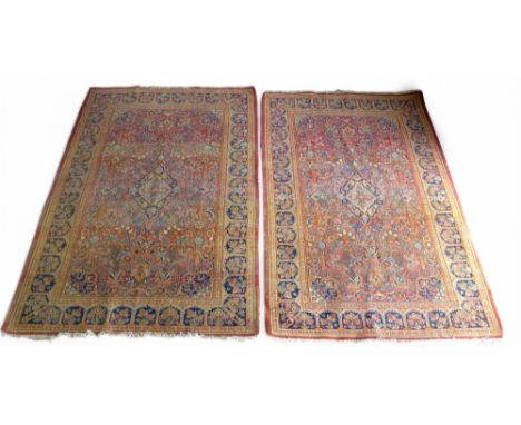 A pair of hand knotted woolen Kashan Persian rugs, with a central medallion on a red field and stylised arch border, 136 by 2