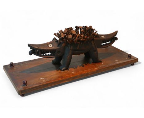 A carved wooden African tribal Nkisi Kozo two-headed dog model, in laid with glass as well as with numerous nails protuding f