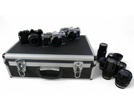 Three Olympus 35mm cameras and lenses comprising two OM-1n bodies and a OM-2n body and eight OM-System lenses contained in a 