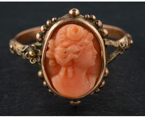 A carved coral cameo ring, depicting the head of a lady in profile, within cannetille surround, stamped 'K12', length of ring