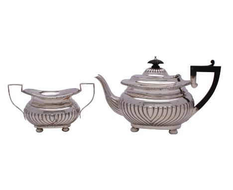 An Edward VII silver teapot and matching sugar basin, maker William M. Hayes, Birmingham 1902 of barge shape with half wrythe