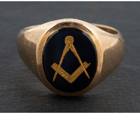 A 9ct gold masonic ring, onyx inset with gold compasses, length of ring head ca. 1.5cm, ring size R, total weight ca. 7.5gms.