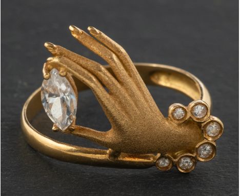 A hand-shaped ring, set with CZ, stamped '750', length of ring head ca. 1.7cm, ring size P, total weight ca. 2.9gms. 