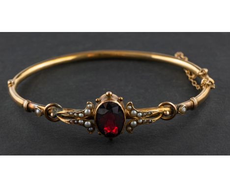An oval, mixed-cut garnet and seed pearl, hinged bangle, estimated garnet weight ca. 4.5cts, stamped '9CT', inner diameter ca