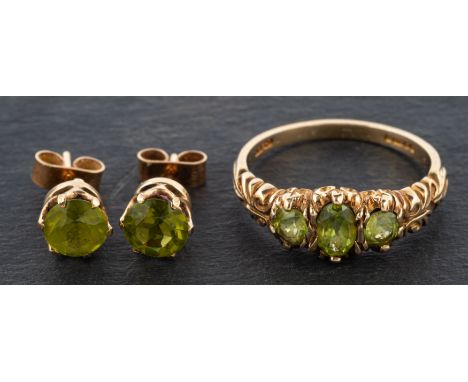 A 9ct gold, oval, mixed-cut peridot, three-stone ring and round, mixed-cut peridot ear studs, with post fittings, the ring wi