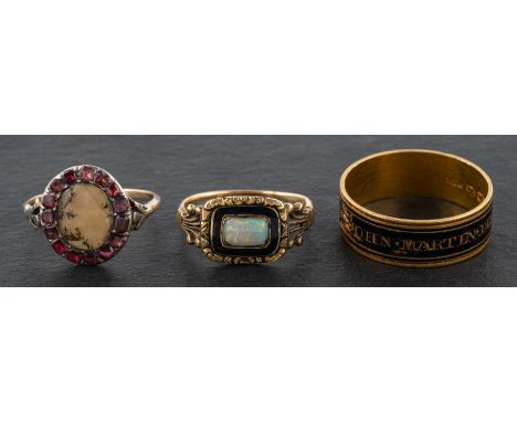 Three 19th century rings, including a Georgian, black enamel mourning ring; a black enamel and cabochon-cut opal ring; and a 