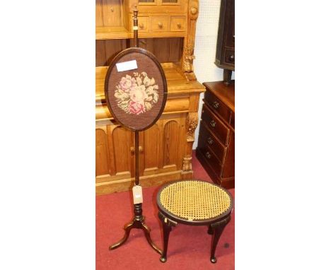 An early 20th century walnut pole screen with floral tapestry inset, together with an oval cane topped dressing stool (2)