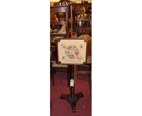 A George IV rosewood pole screen, the needlework banner with rise-and-fall action, on a ring turned column to a gadrooned tri
