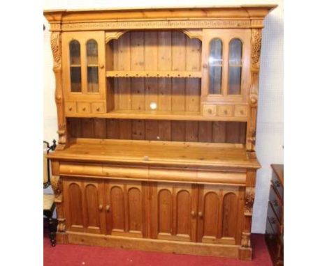 A contemporary stained pine kitchen dresser, the upper section having open central shelves flanked by glazed doors over short