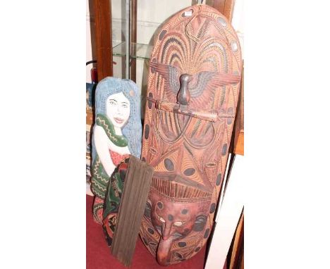 A carved and painted softwood tribal shield, h.146cm; together with a smaller example, h.66cm; a relief carved and painted pa