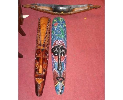 Two South East Asian carved soft wood elongated face masks, together with a further model boat (3)