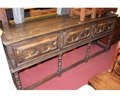 An early 20th century Jacobean style geometric moulded oak long dresser base, having twin frieze drawers, the central twin cu