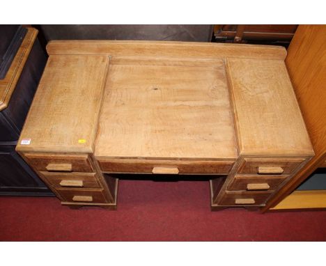 A 1930s faded light oak kneehole dressing table, having an arrangement of seven drawers, width 107cm