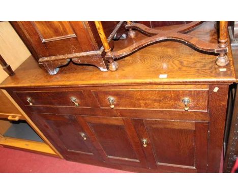 An early 20th century oak dresser base, having twin frieze drawers over twin cupboard doors with central fixed panel, width 1