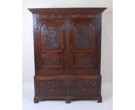 An 18th century joined oak livery cupboard, having twin blind carved panelled doors, opening to reveal unfitted interior, the