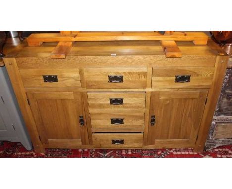 A contemporary light oak sideboard fitted with six drawers and opposing lower panelled cupboard doors, width 140cm