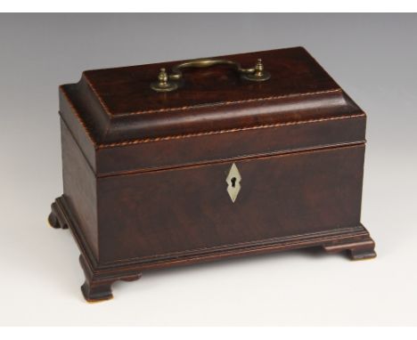 A George II mahogany tea caddy, the hinged pagoda cover with brass swing handle, inlaid with chevron banding, opening to reve