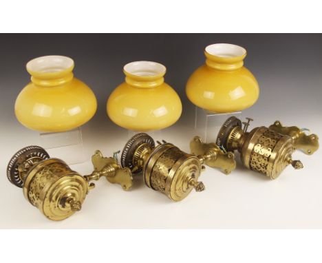 Three brass oil lamp wall sconces, late 19th century, the Duplex burner reservoirs seated within cylindrical galleries pierce